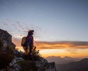 Women in climbing gear standing on edge of cliff.