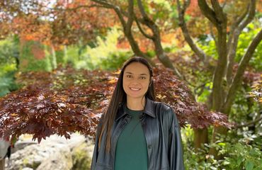 Portrait of Astrid Peraza standing outside with trees behind her.