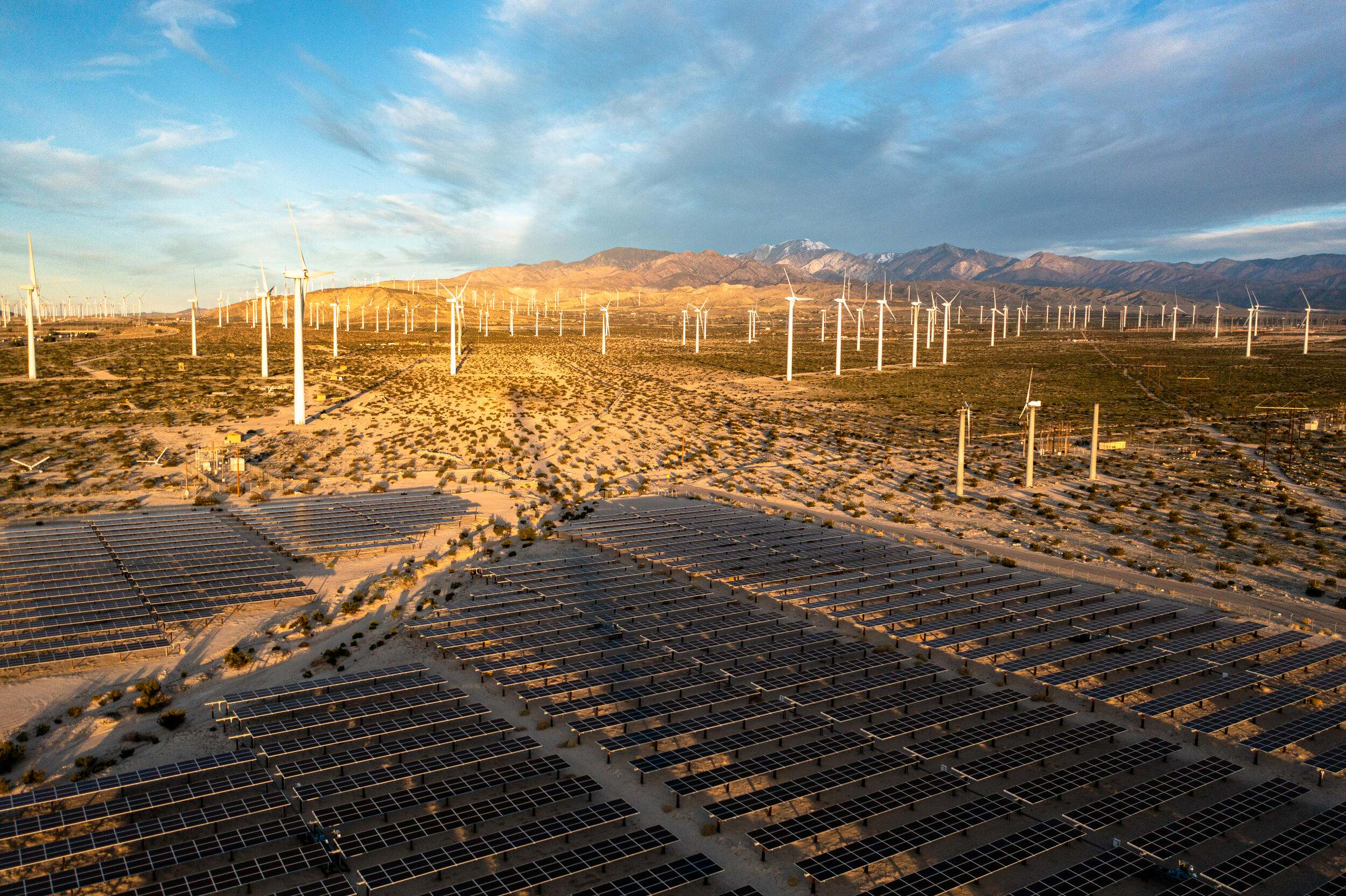 Desert landscape with solar panels and wind turbines.