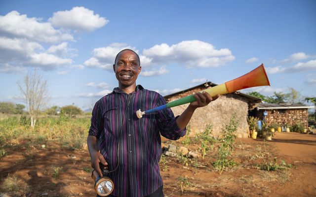 A person holding a flashlight and colorful plastic horn.