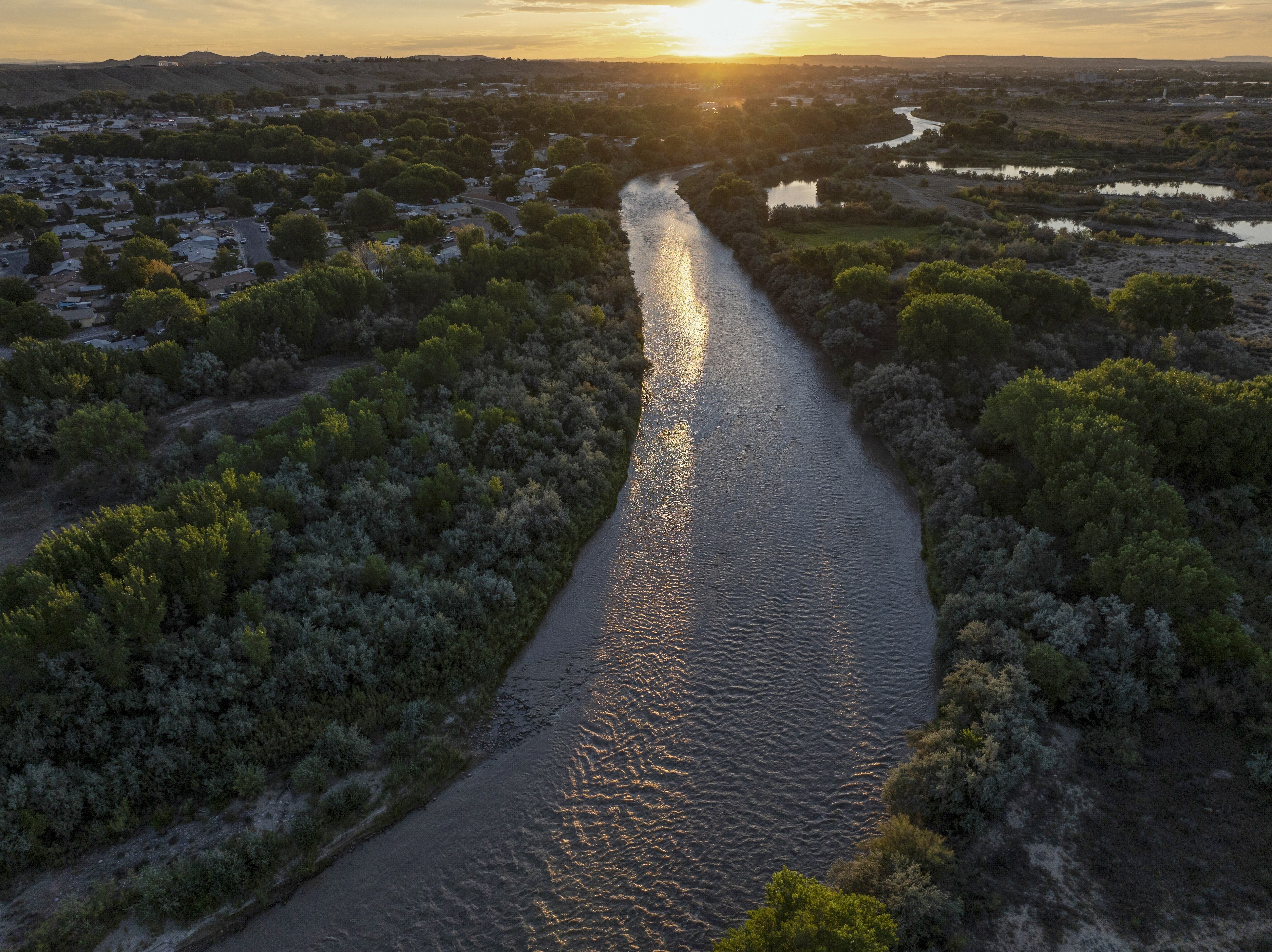 Aerial view of a wide river flowing through a forest.
