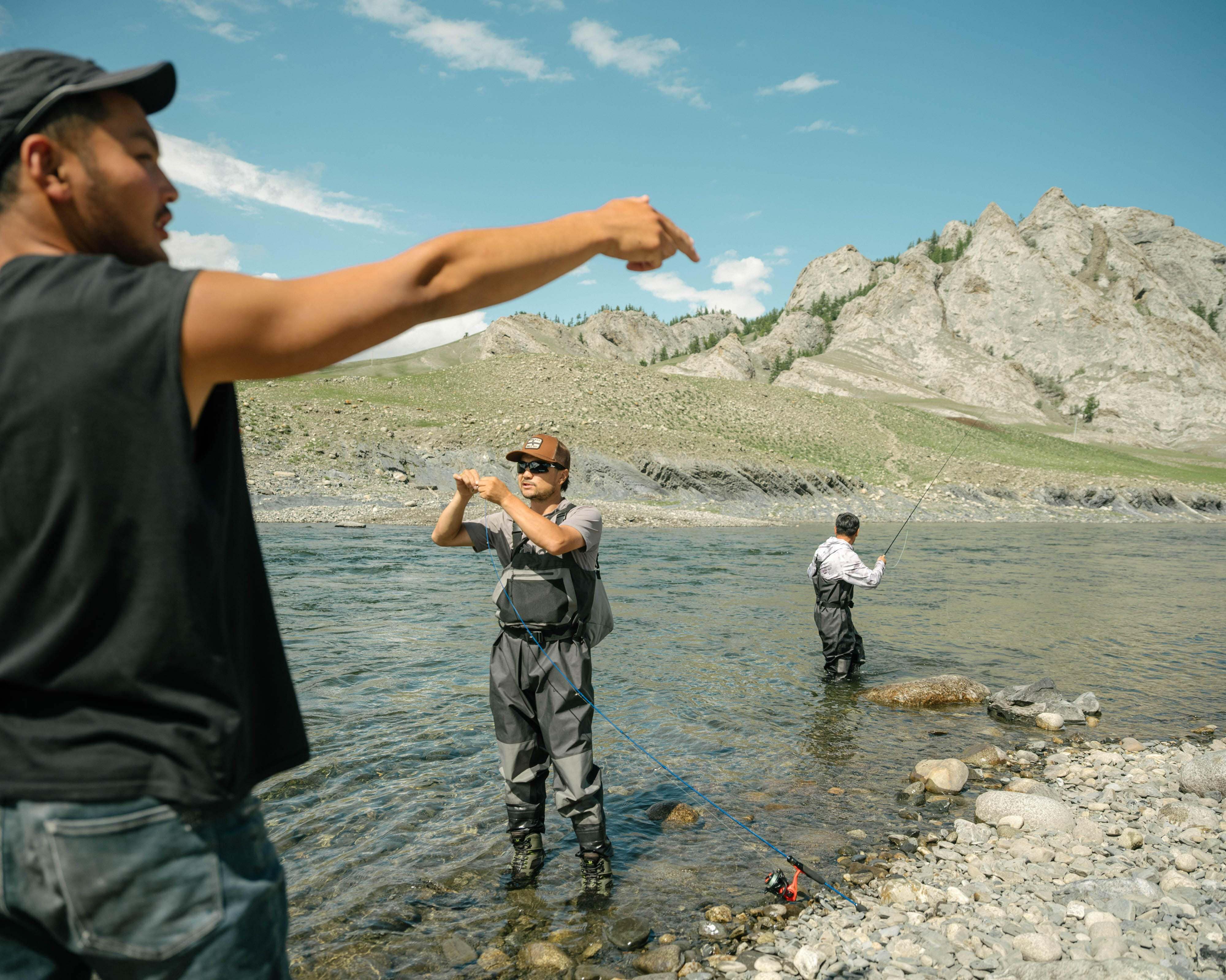 A man pointing to a man standing in water with other men in the background.