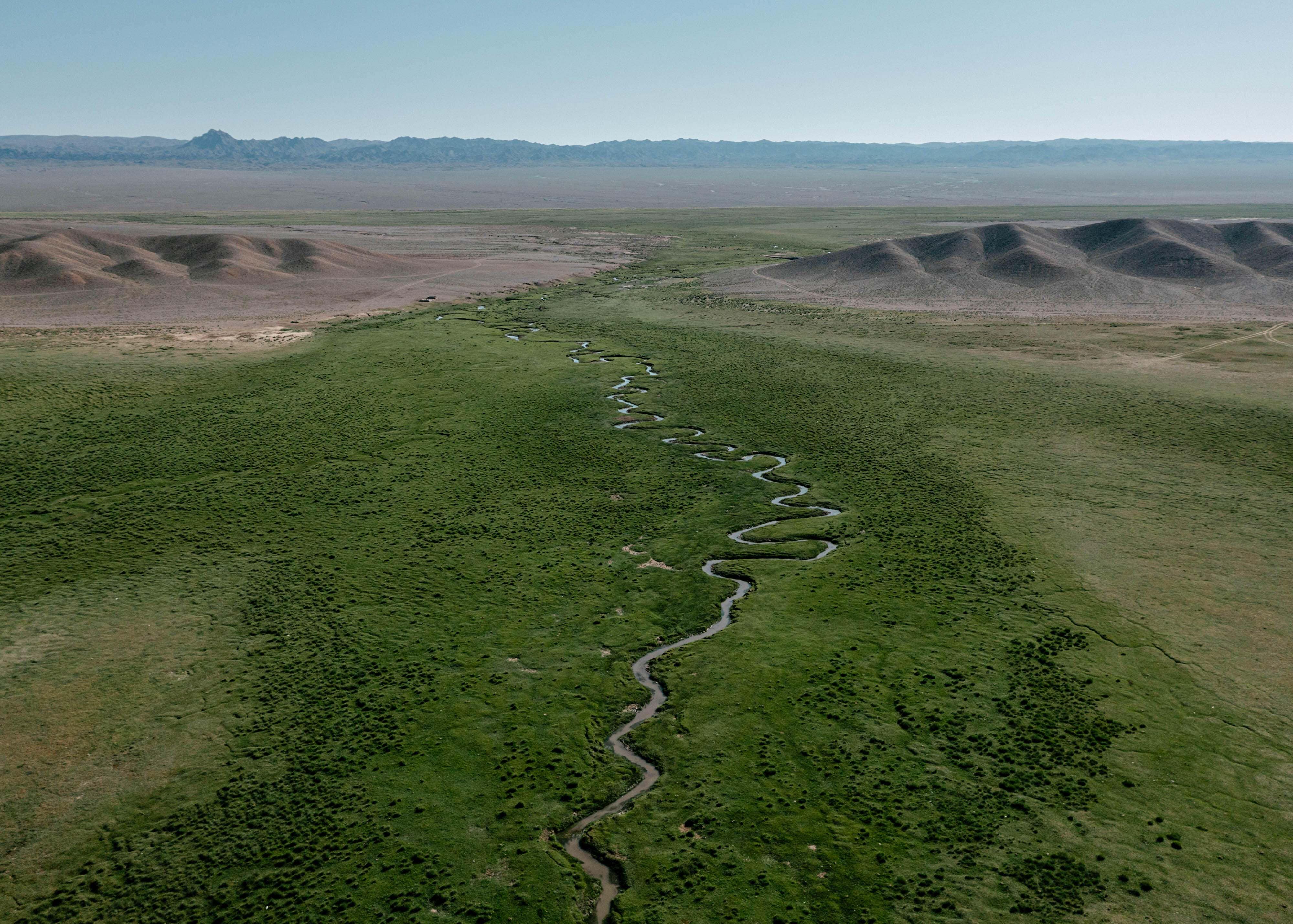 A large field with a river running through it.