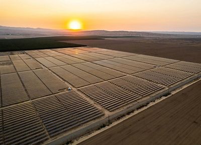 sun sets behind a solar farm.
