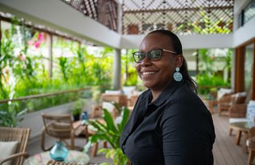 Marie-May Jeremie stands in room with tables.
