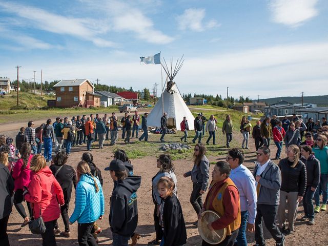 Men women and children of lutsel ke first nation dance in a circle near a tipi in a first nations native american community