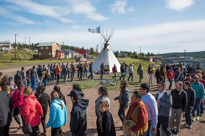Men women and children of lutsel ke first nation dance in a circle near a tipi in a first nations native american community
