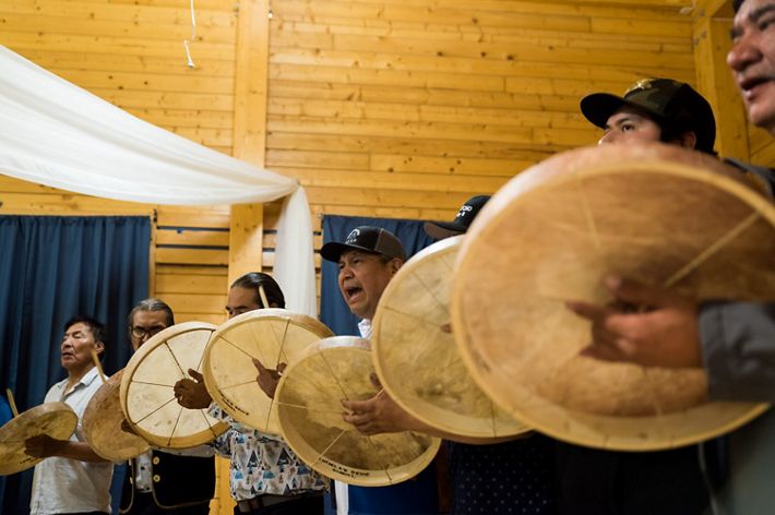 first nation native american men beating drums during a ceremony 