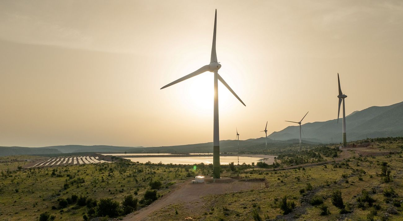 The sun sets behind wind turbines.