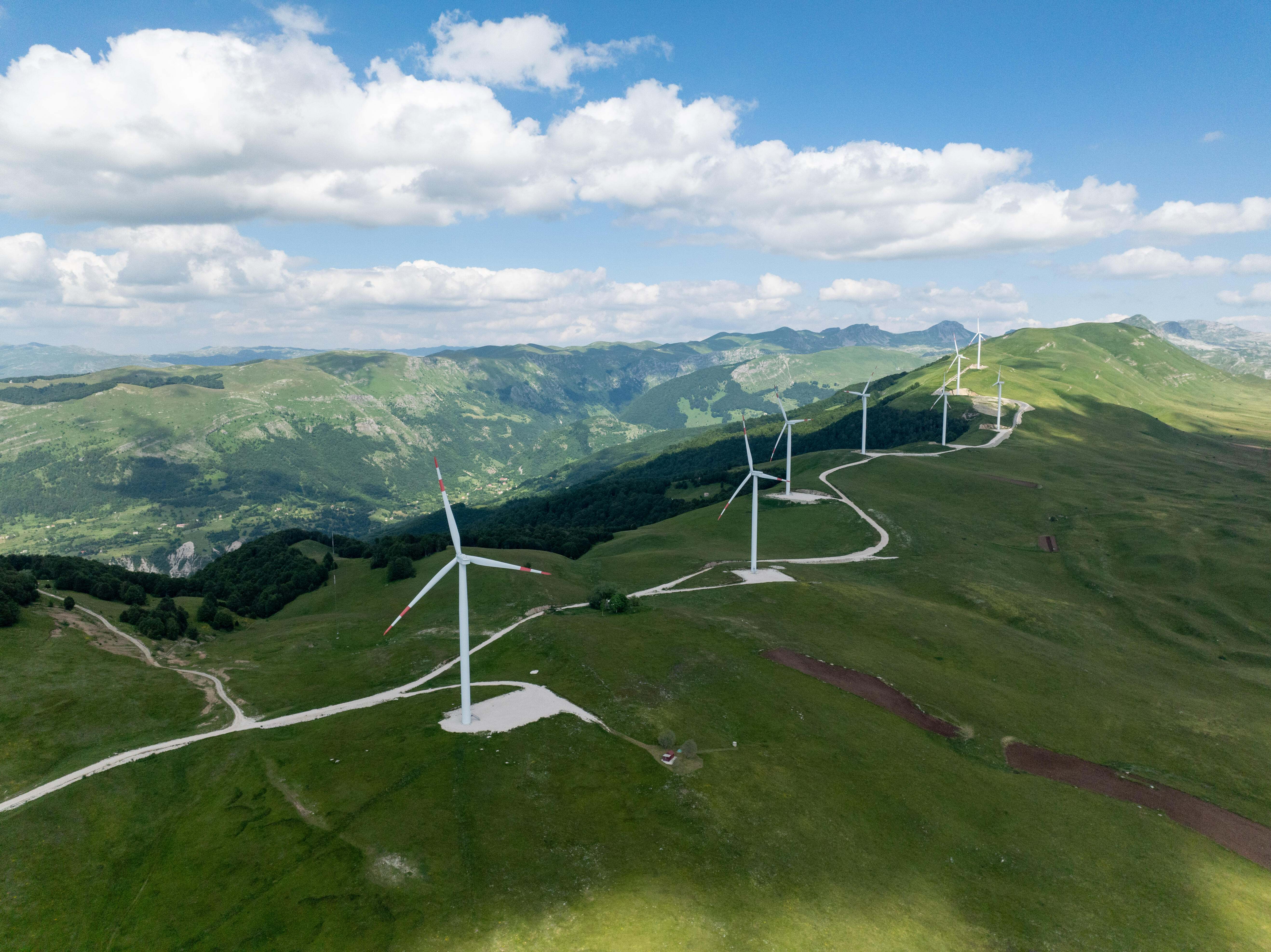 Row of wind turbines along winding mountain road.