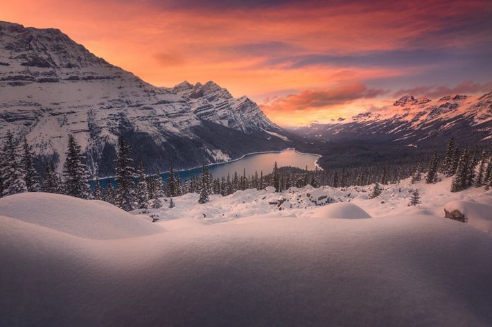 Glowing clouds illuminate snowy mountain lake.