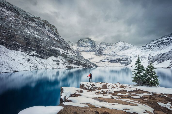 Lone hiker along snowy mountain lake