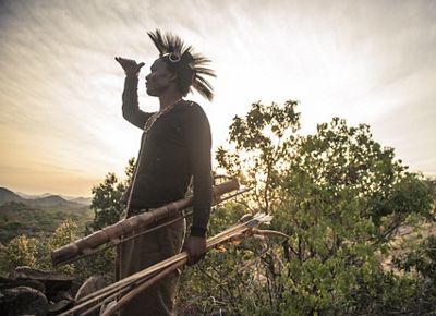 Backlit by a bright sun, a man wearing a traditional he