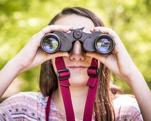 Dramatic landscape view of sand dunes overlooking a beach and ocean under a cloud-filled sky colored in blue and orange.