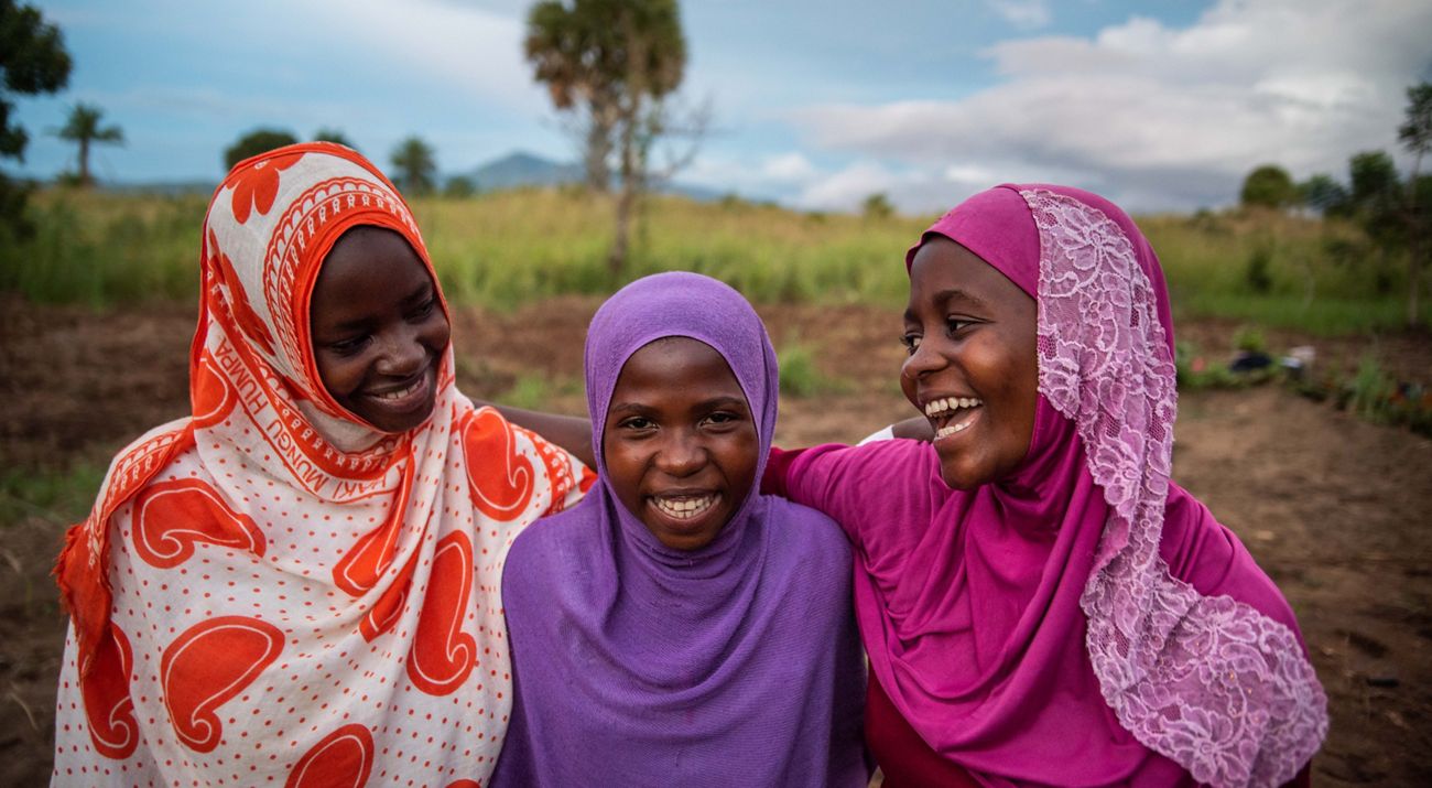 three girls standing together and smiling.